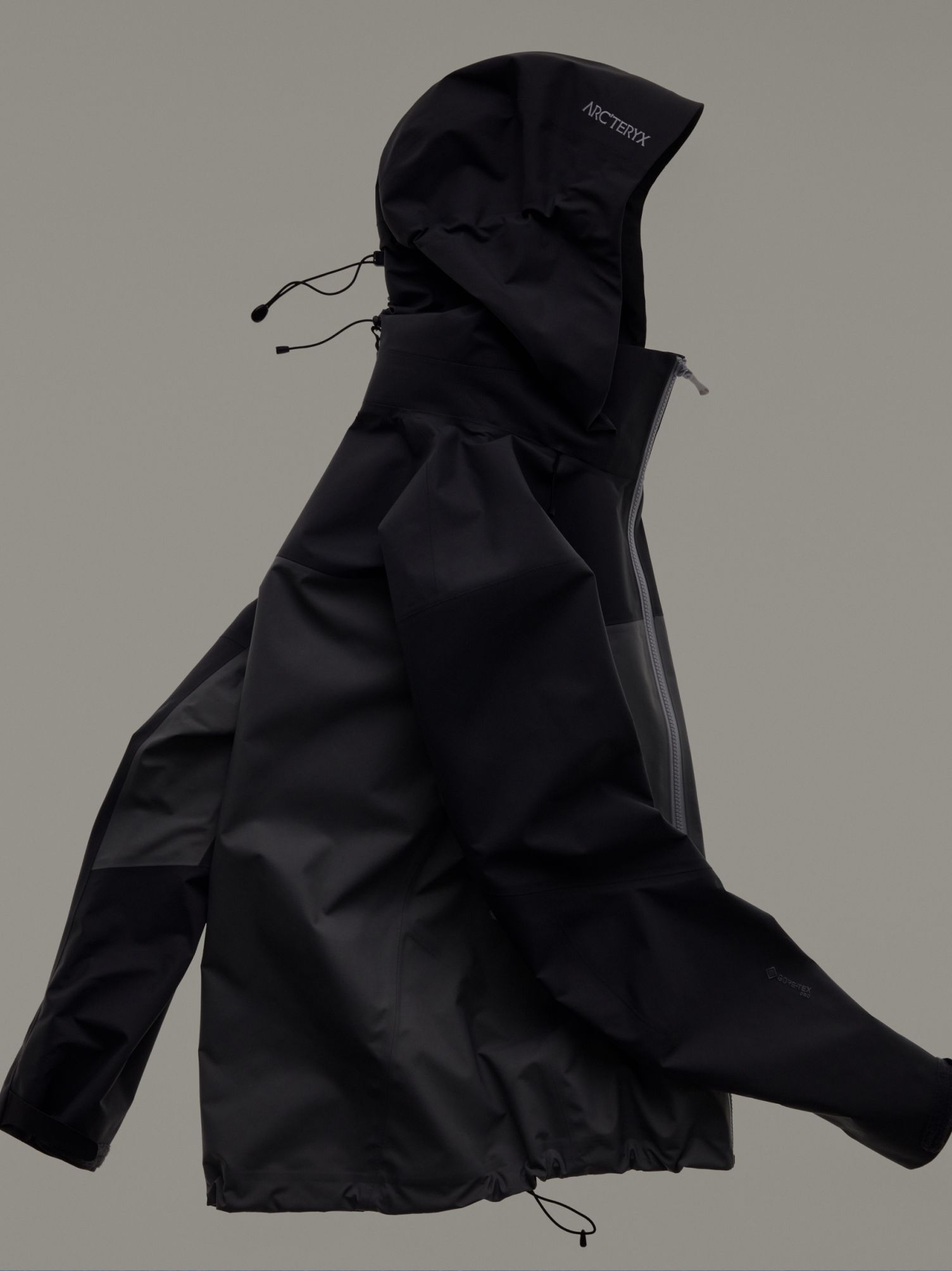 Black Arc'teryx technical jacket next to a close-up of its dark, patterned fabric.
