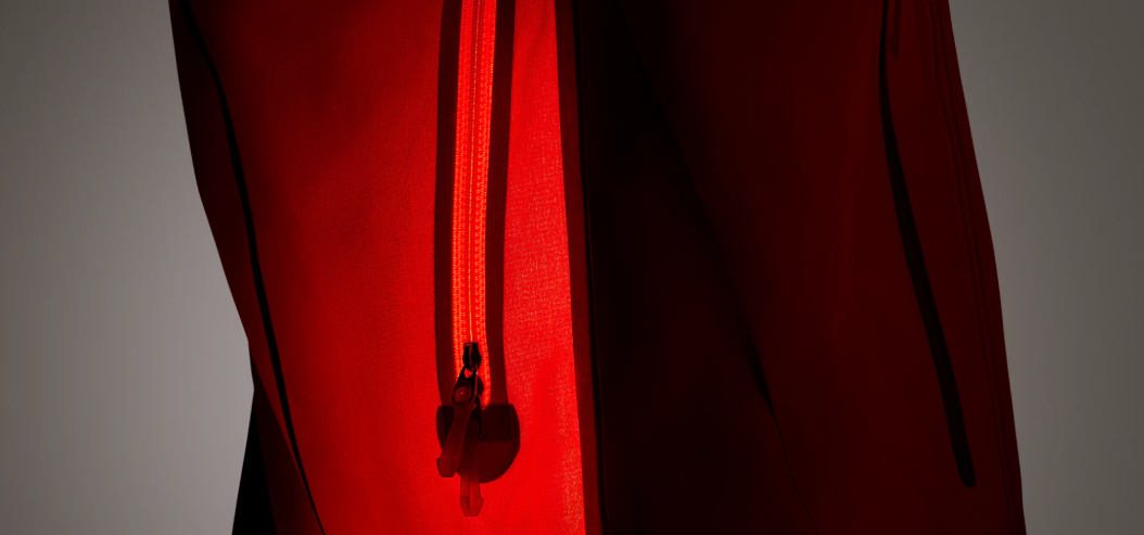 A bright red zipper with a pull tab on deep red fabric.