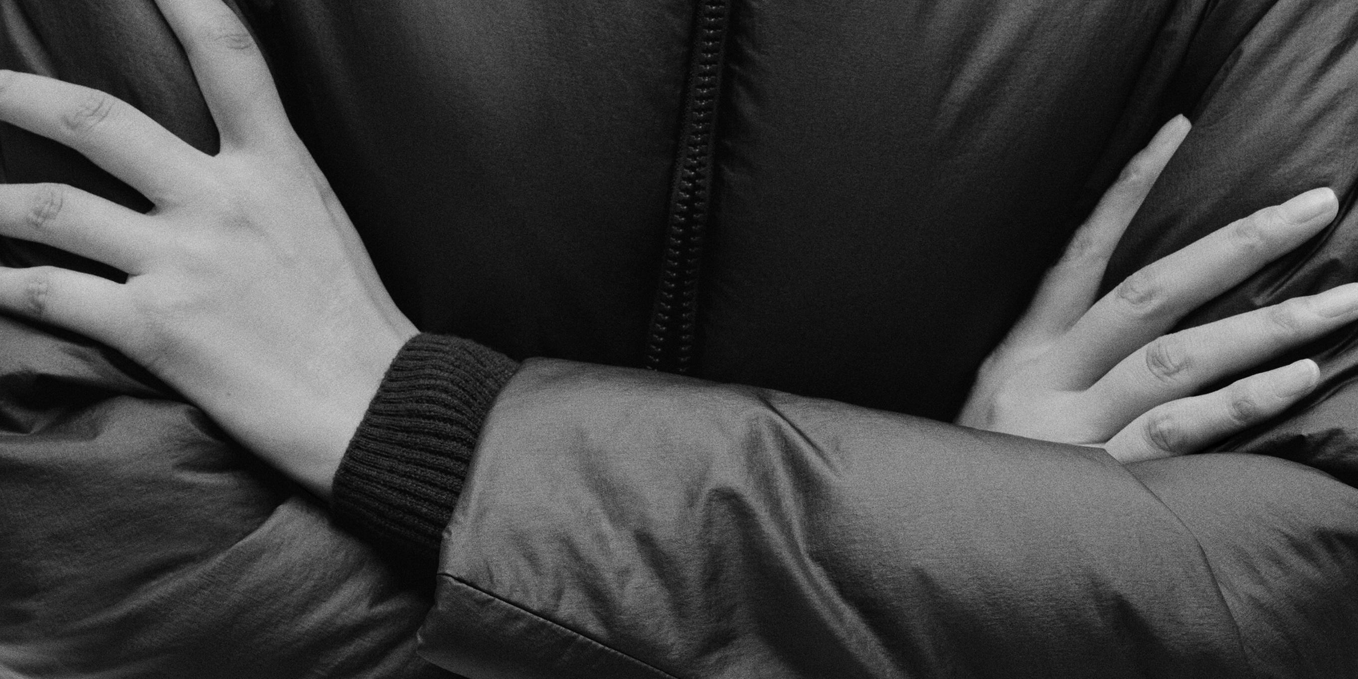 a black and white photo of a person with their arms crossed .