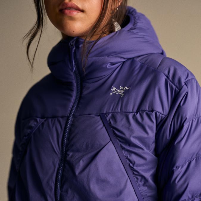 Close-up of a person wearing a purple Arc'teryx hooded puffer jacket.