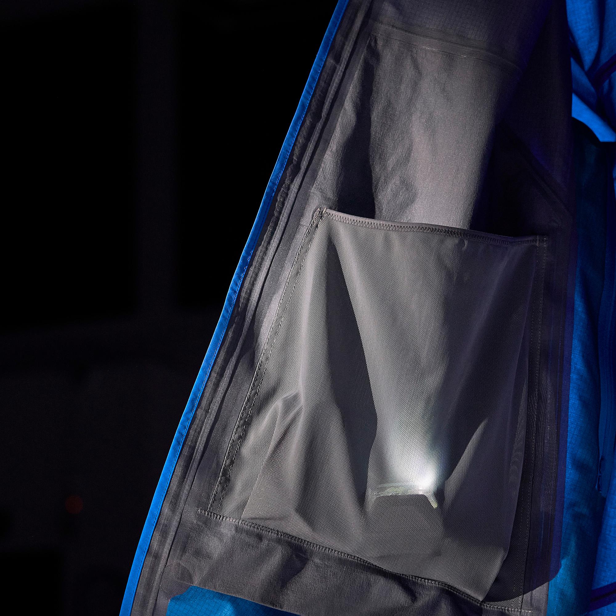 Internal view of a blue jacket showing a lit mesh pocket and sealed seams.