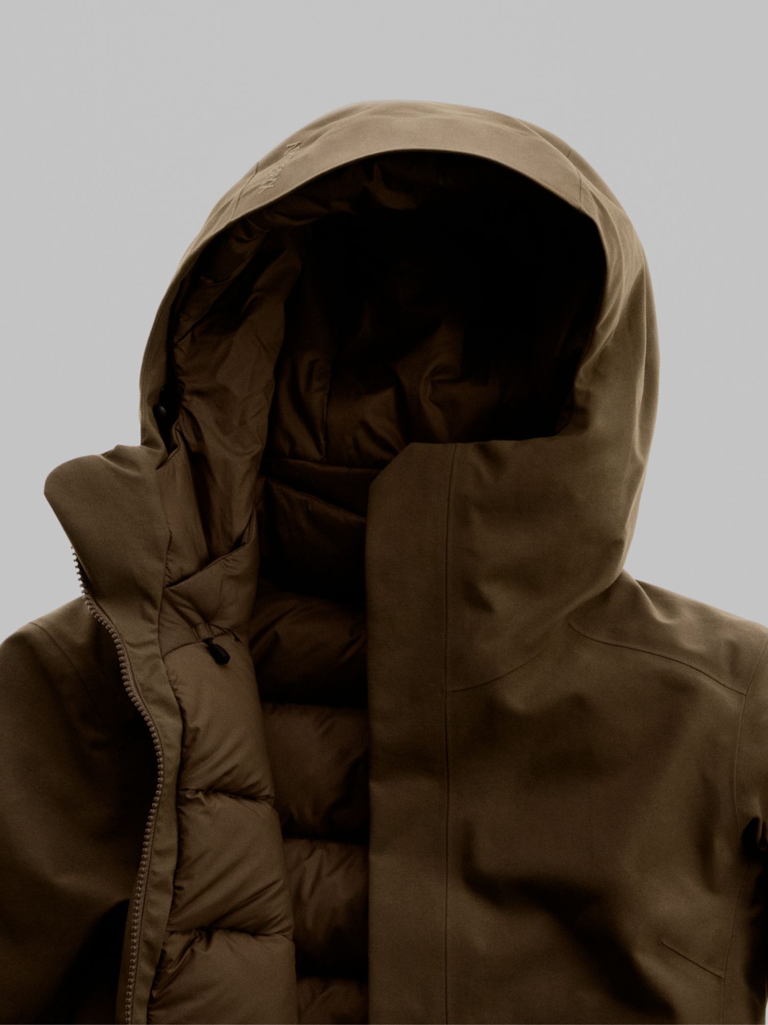 Black Arc'teryx technical jacket next to a close-up of its dark, patterned fabric.