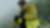 Person in a yellow-green rain jacket and gloves adjusting their gear in a snowy, foggy mountain environment.