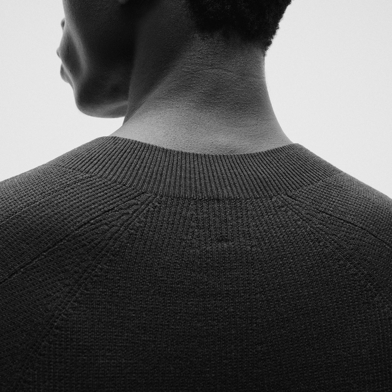 a black and white photo of a man wearing a black sweater.