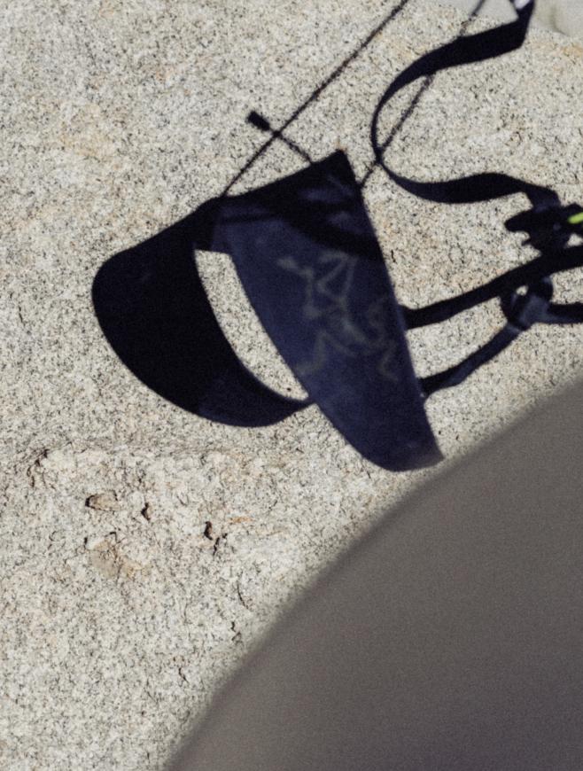 Shadow of Arc'teryx climbing gear on a granite surface.