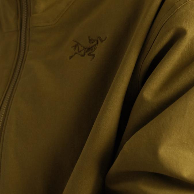 Close-up of a dark olive green jacket with the Arc'teryx logo and a zipper.