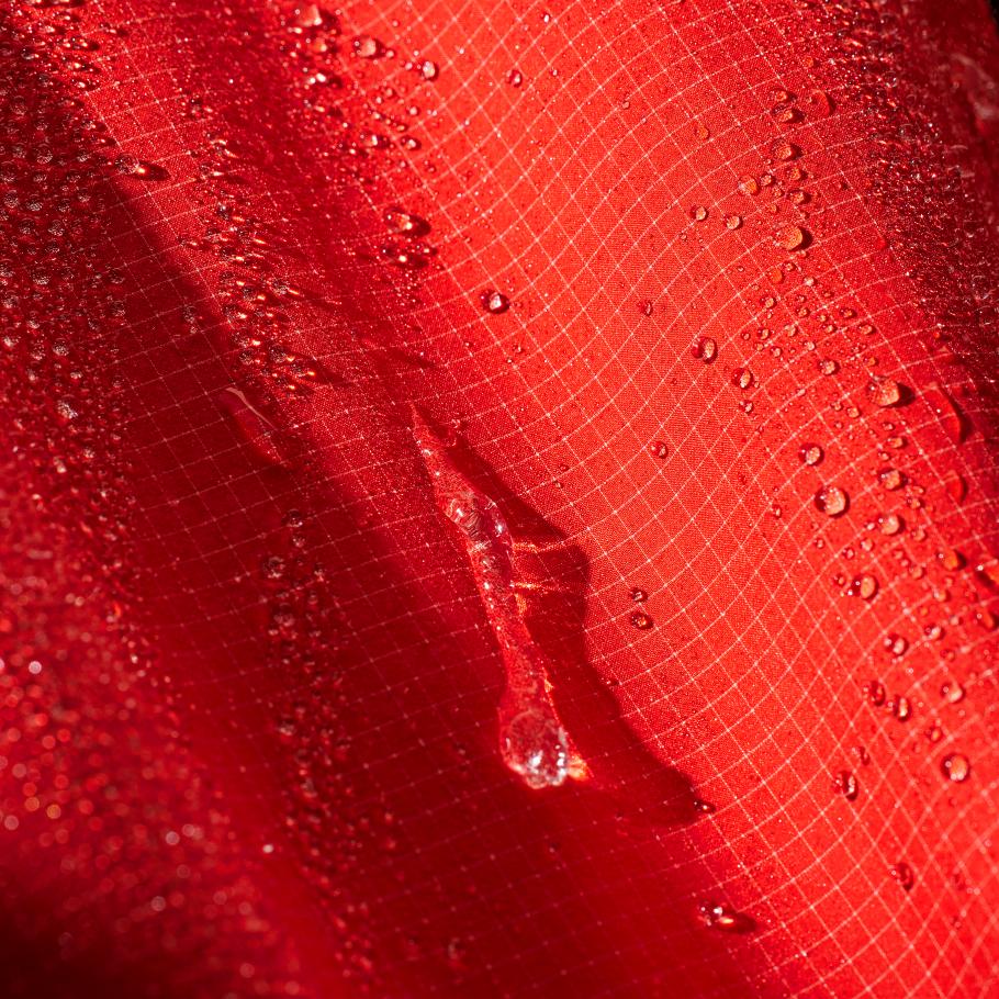 a close up of a red waterproof shell jacket with water drops on it