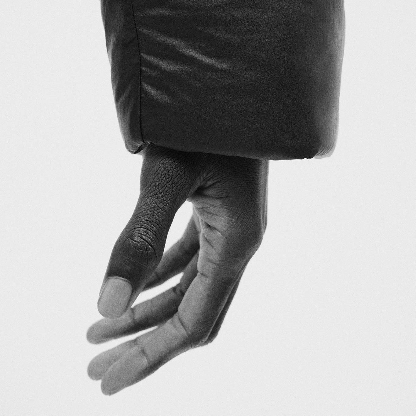 a black and white photo of a person's hand wearing a black jacket.