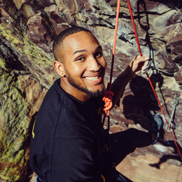 a man is smiling while climbing a rock wall