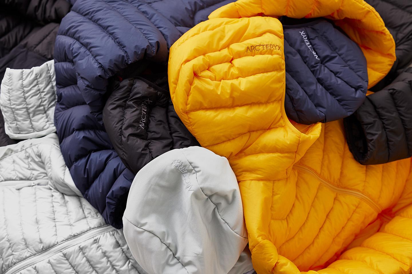 a pile of different colored down jackets are stacked on top of each other