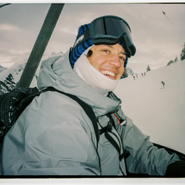 a person wearing goggles and a scarf is sitting on a ski lift .