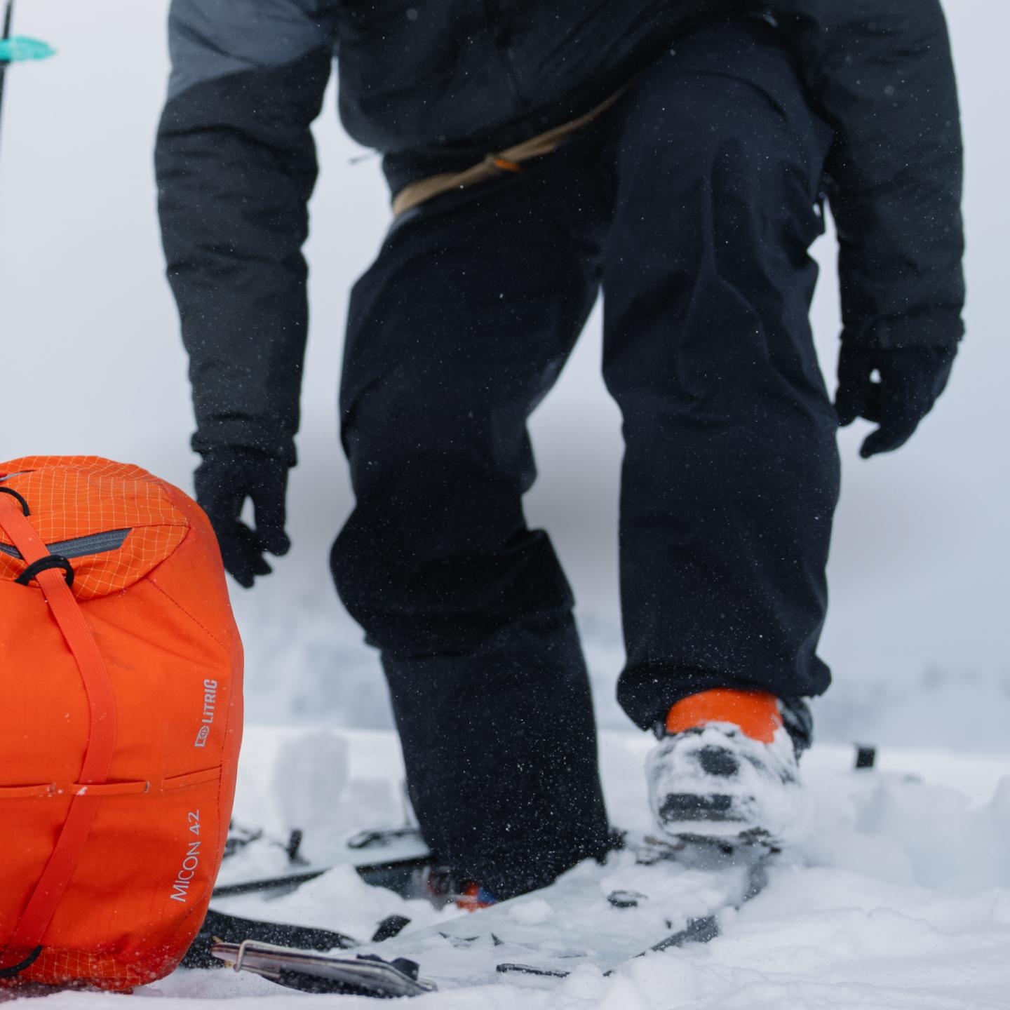 a person is standing in the snow with skis and a backpack .