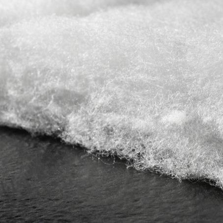 Fluffy white synthetic insulation on a dark background.