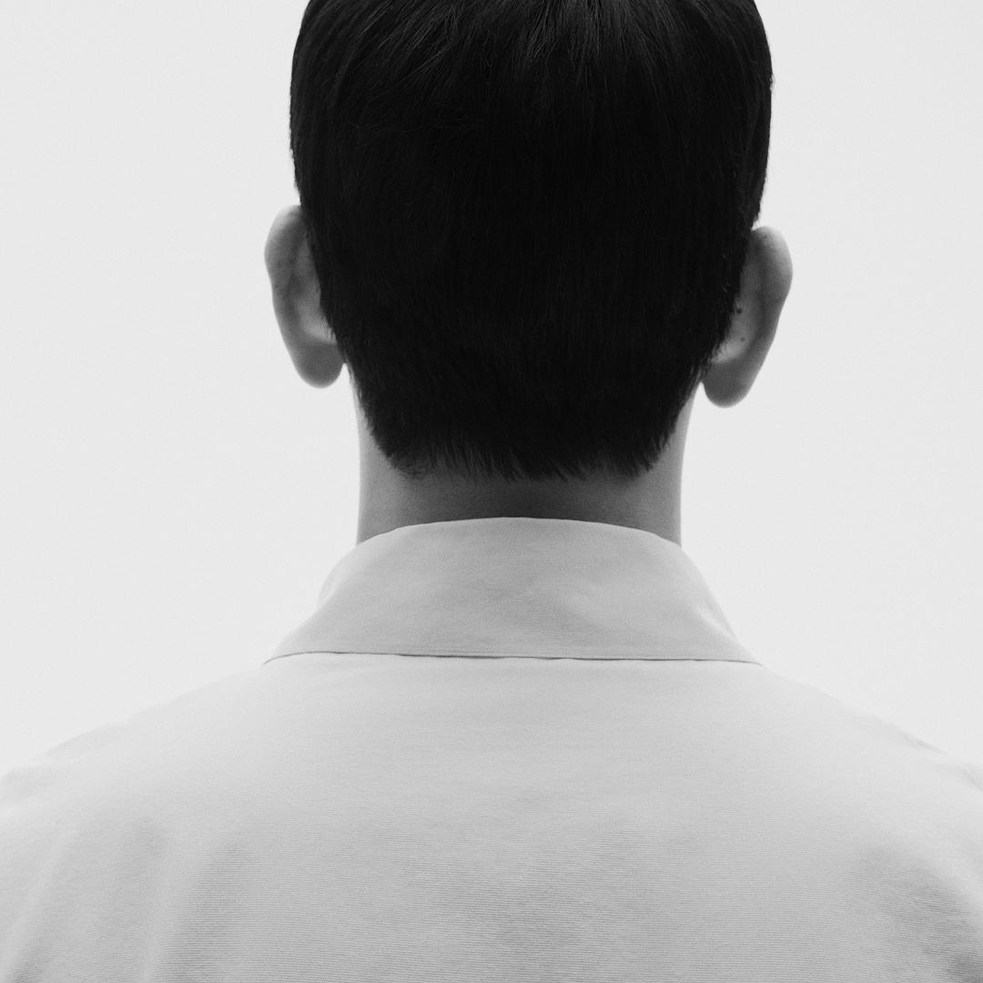 Black and white image of the back of a person's head and shoulders.