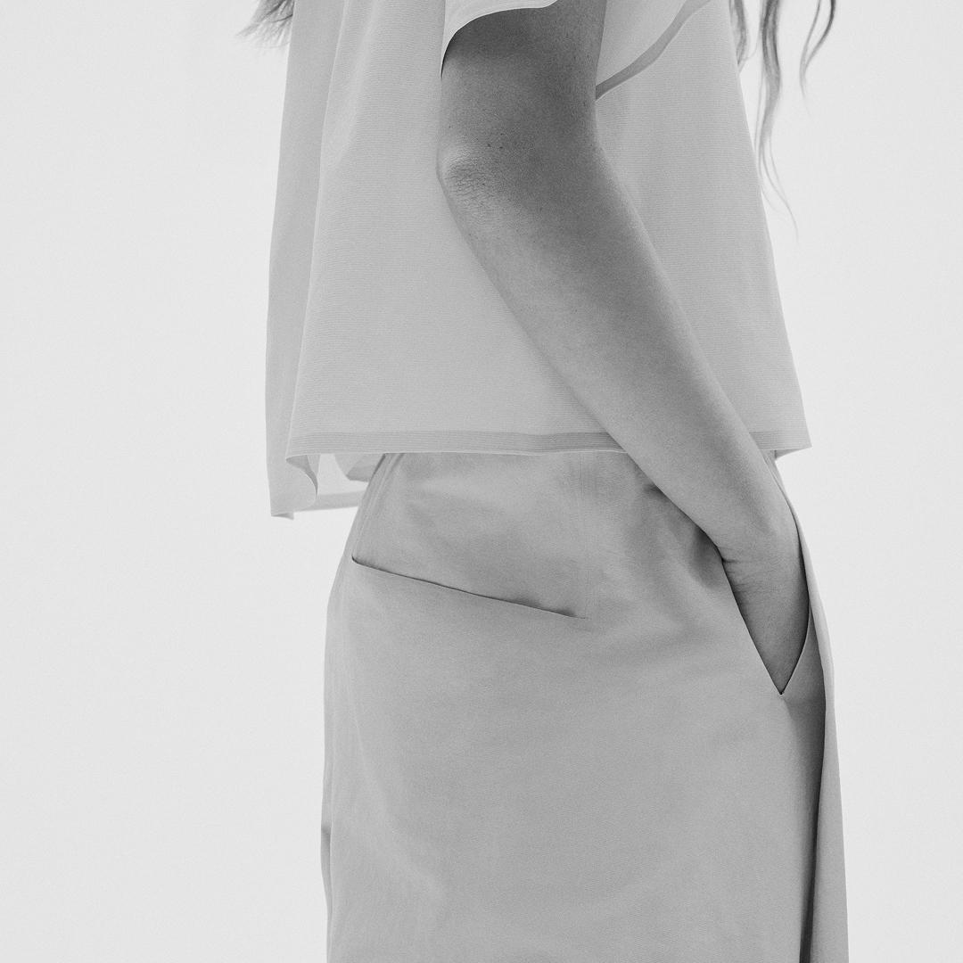 Black and white image of a person with a hand in their pocket.