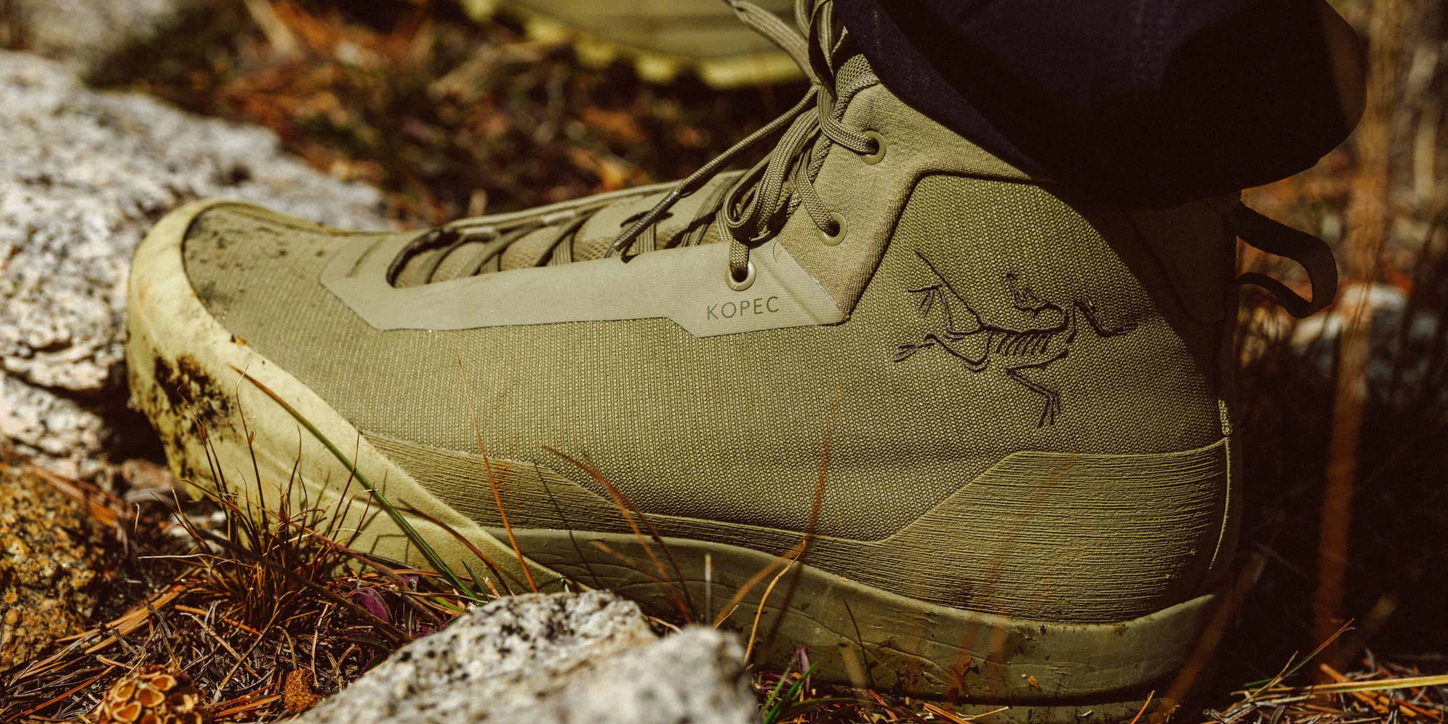 Close-up of a dirty, olive-green Arc'teryx Kopec hiking shoe on rocky terrain.