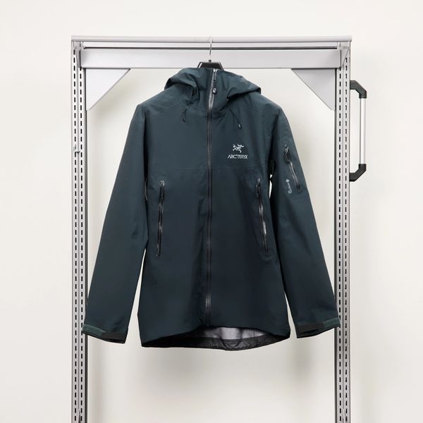 A dark green Arc'teryx hooded jacket hangs on a rolling metal clothing rack.