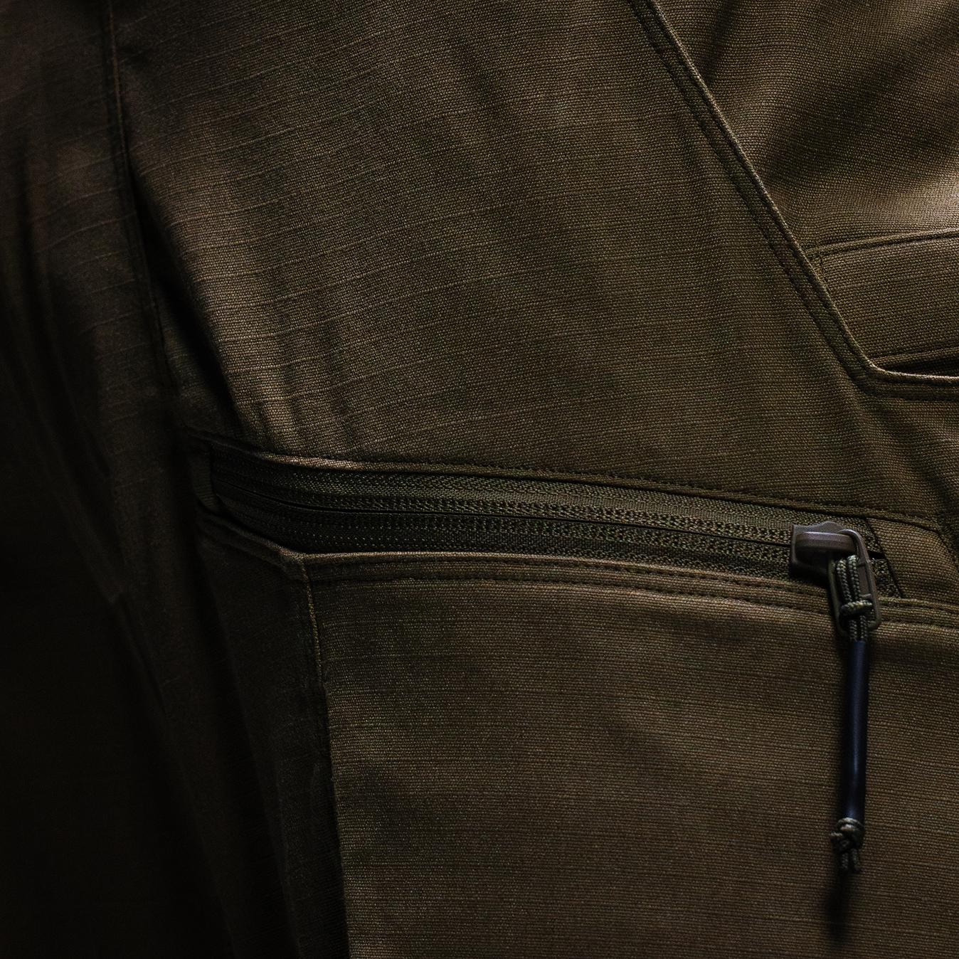 Close-up of olive green ripstop fabric with a zippered pocket.