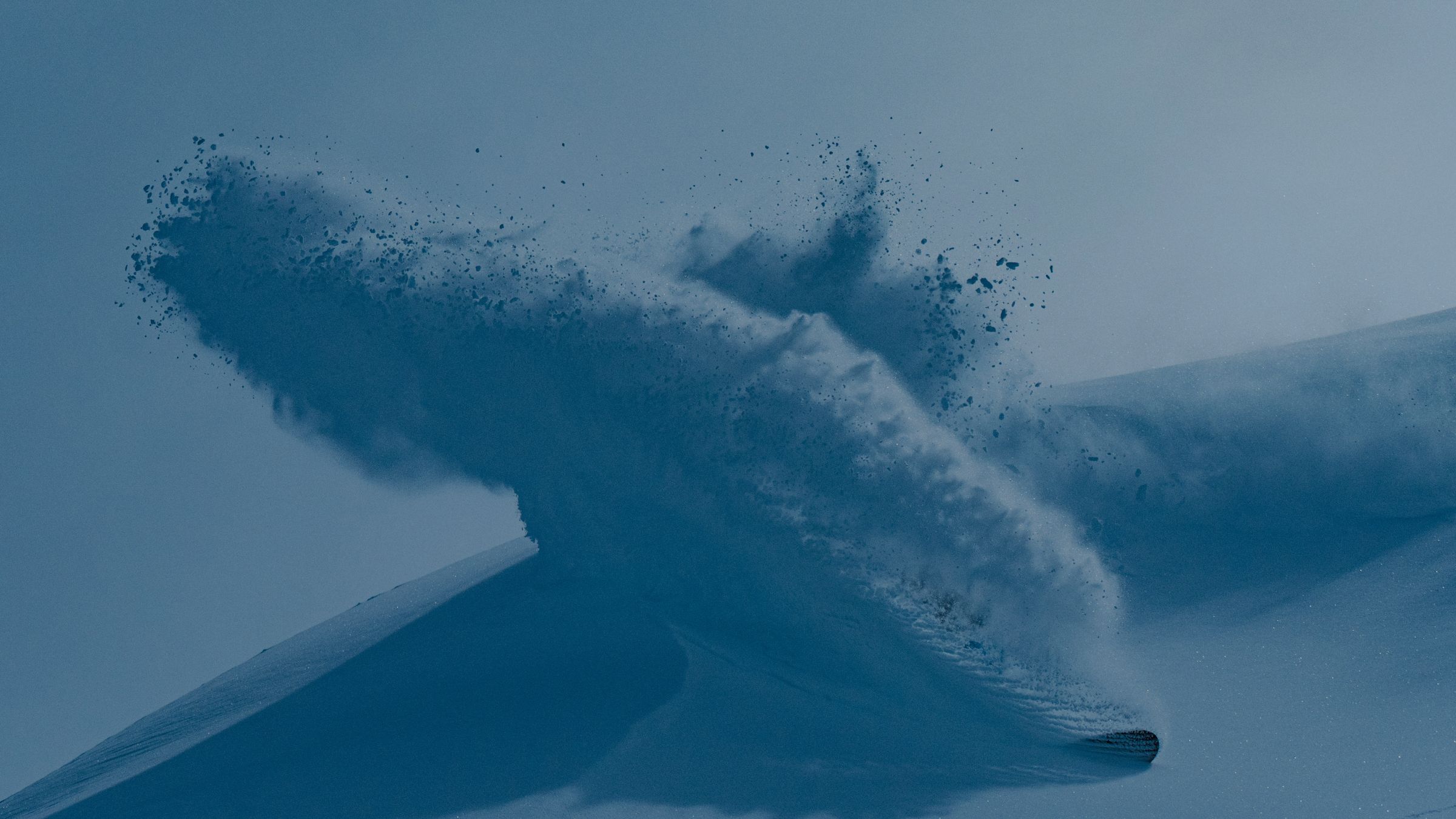 Dark jacket with blue zipper next to snowboarder carving in snow.