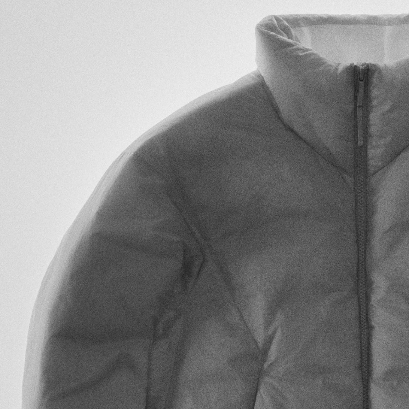a close up of a grey puffer jacket with a zipper on a white background.