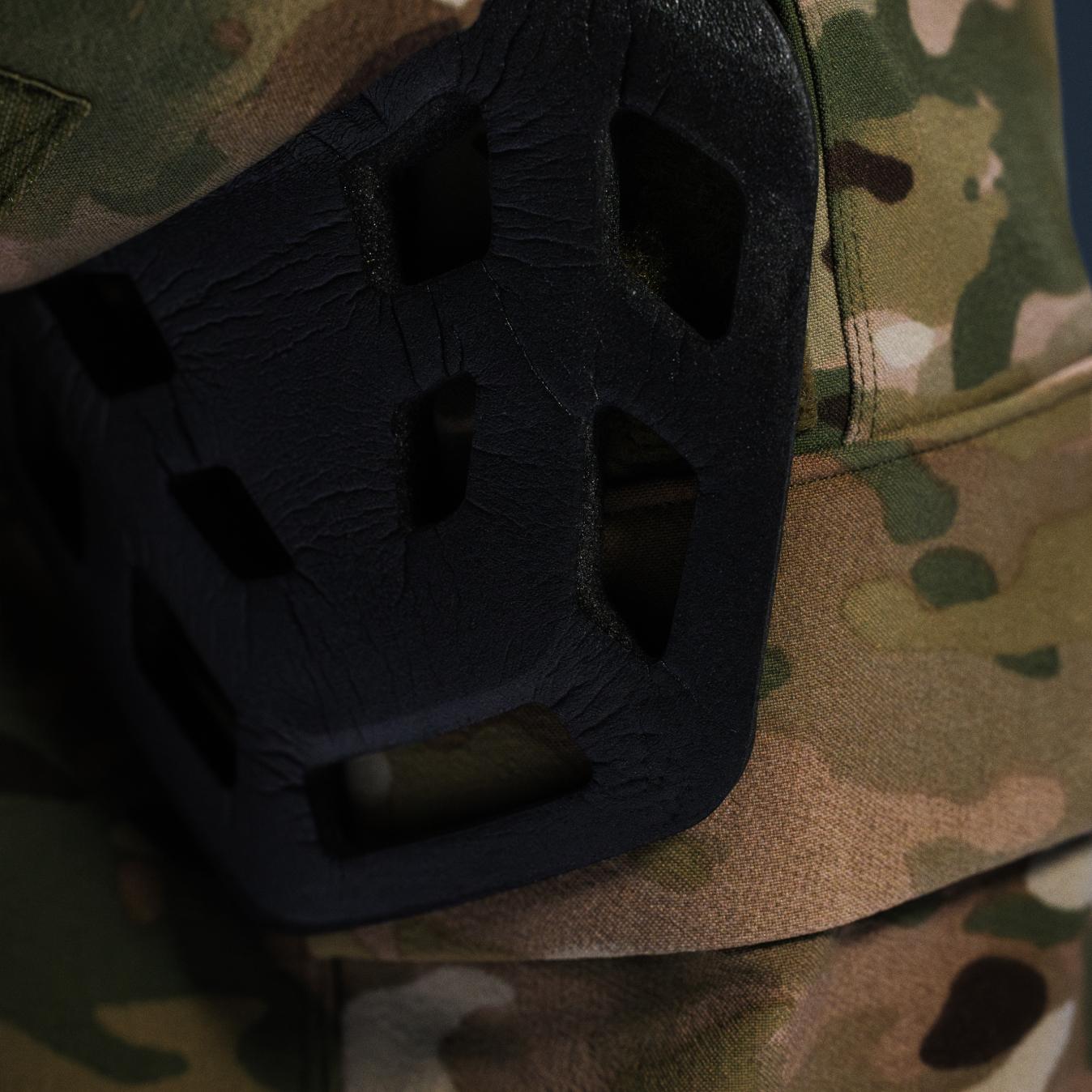 Black, textured, perforated protective pad on camouflage fabric.