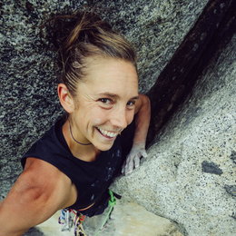 a woman is smiling while climbing a rock wall