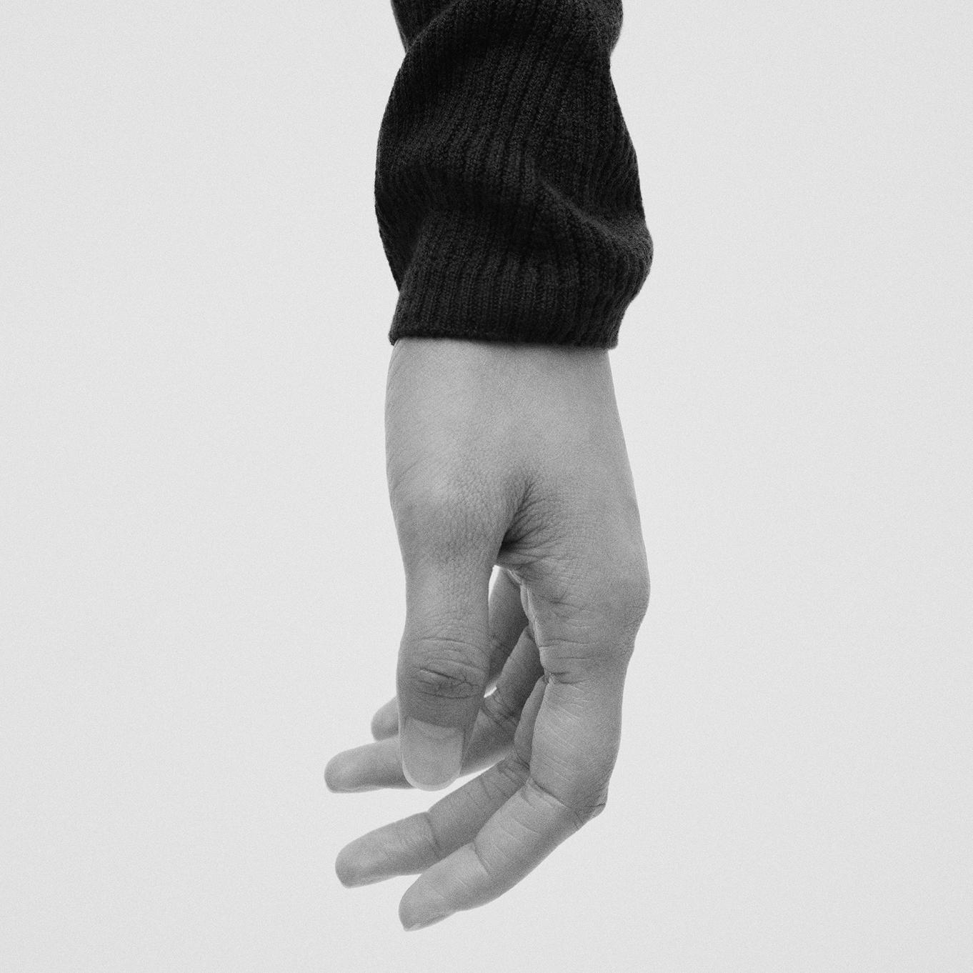 a black and white photo of a person 's hand wearing a black sweater.