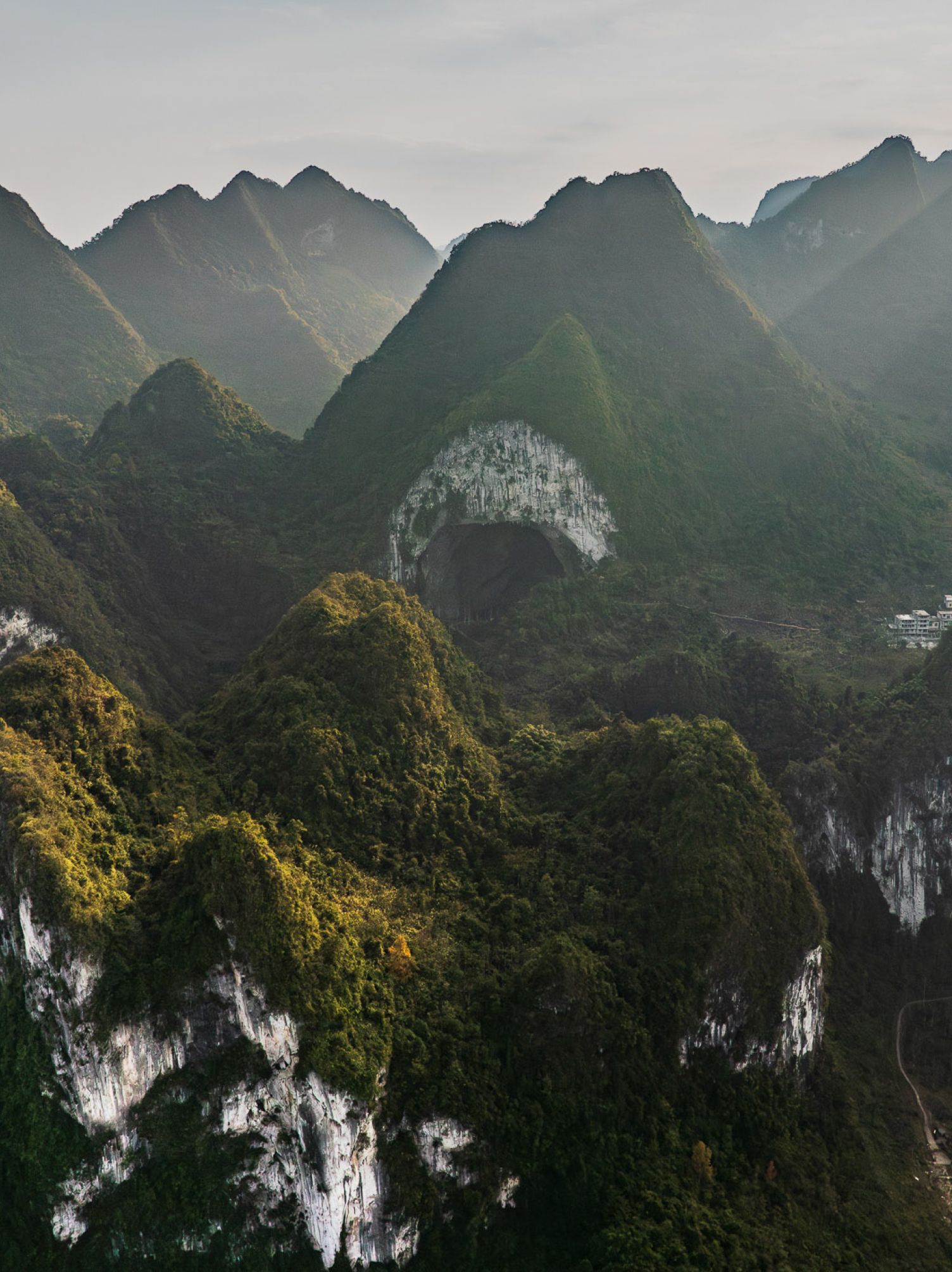 Lush green mountains with a prominent natural rock arch.