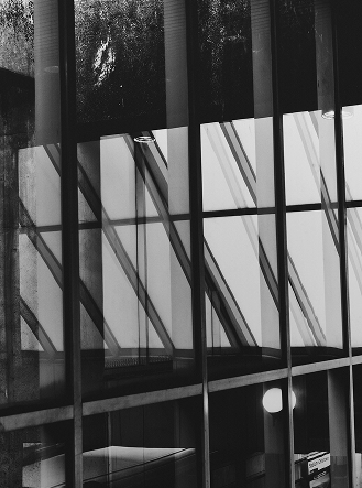 Black and white image of a modern building's glass windows with strong geometric reflections.