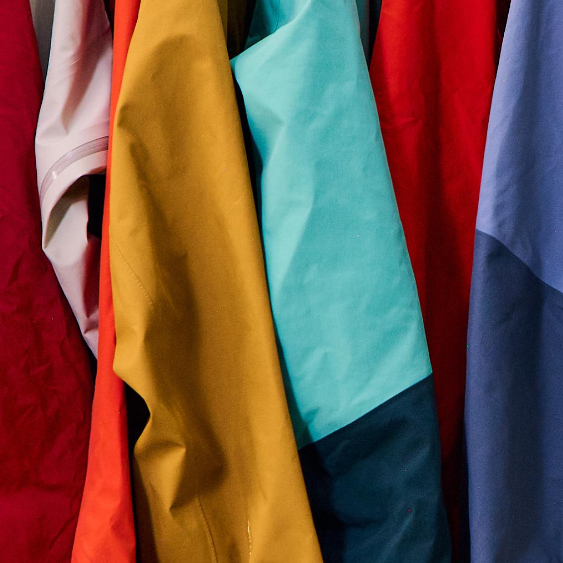 a bunch of different colored jackets are hanging on a rack