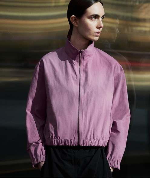 A woman wearing a mauve collared zip-up jacket.