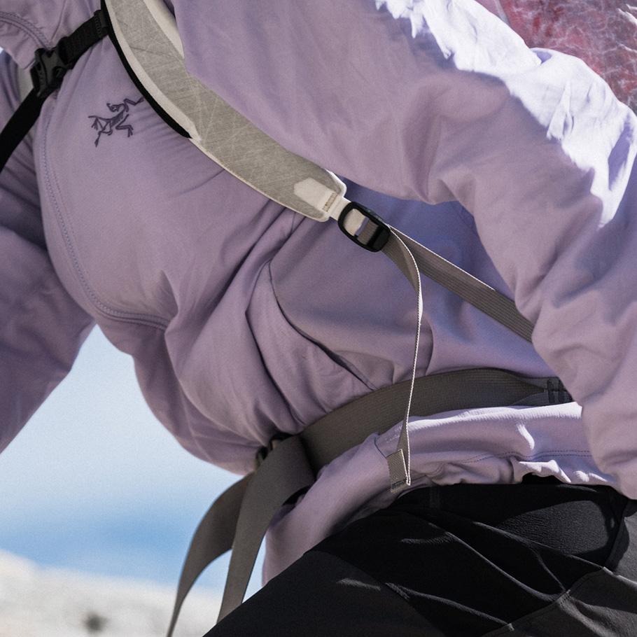 Person wearing a light purple Arc'teryx jacket, backpack, and black pants.