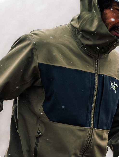 A smiling man with grey hair wears a grey and blue Arc'teryx hooded jacket.