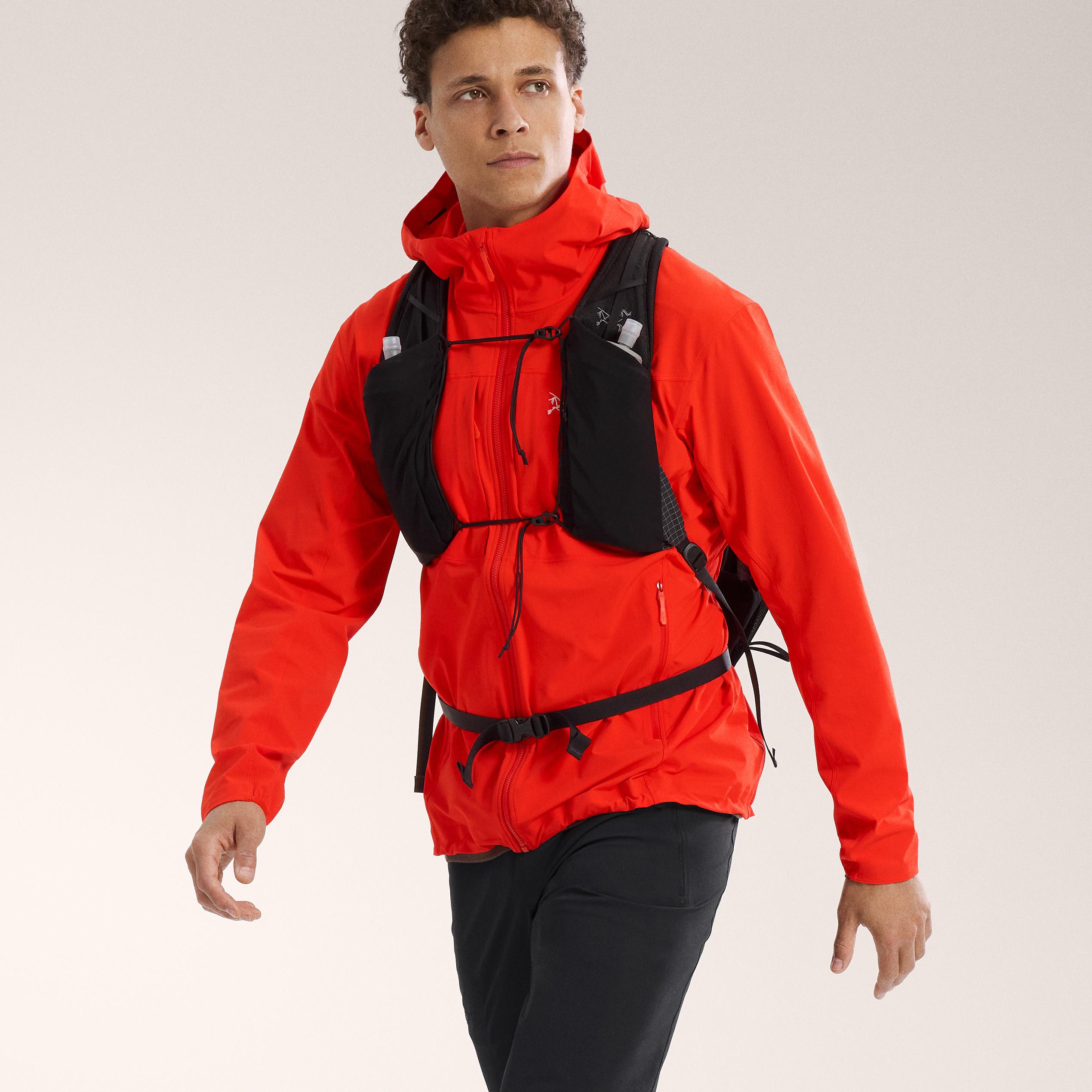 a man wearing a red jacket and a black backpack is walking .