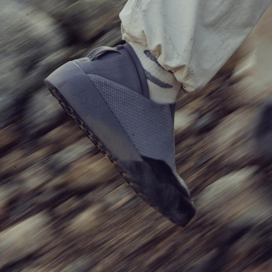Foot in a gray shoe with motion blur over rocky ground.