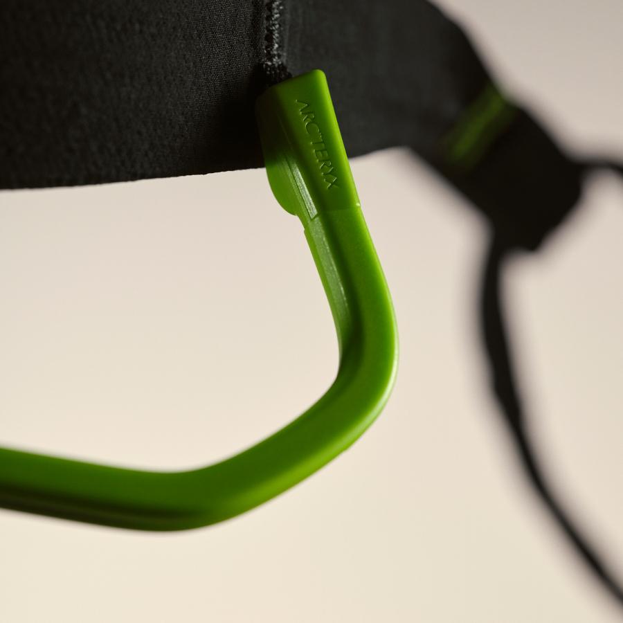 Close-up of a bright green Arc'teryx clip attached to a black strap.