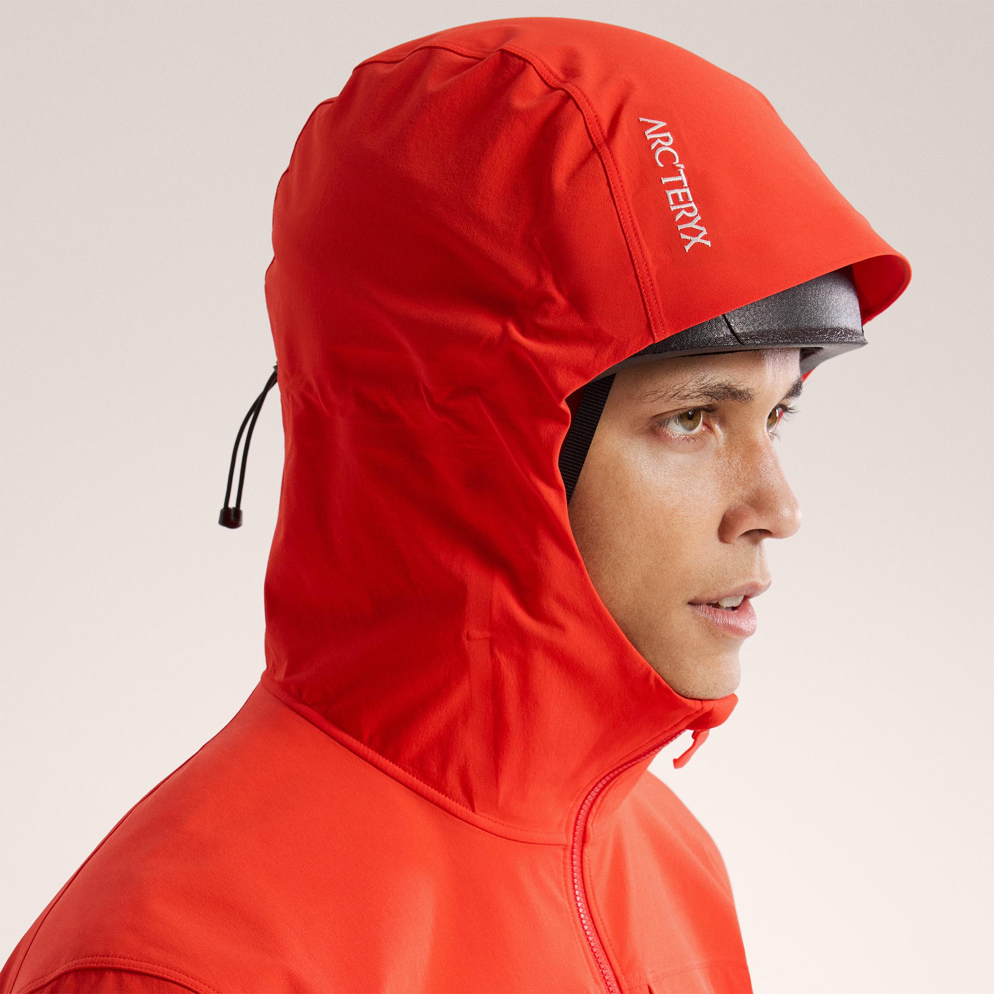 a man is wearing a red jacket with a hood .