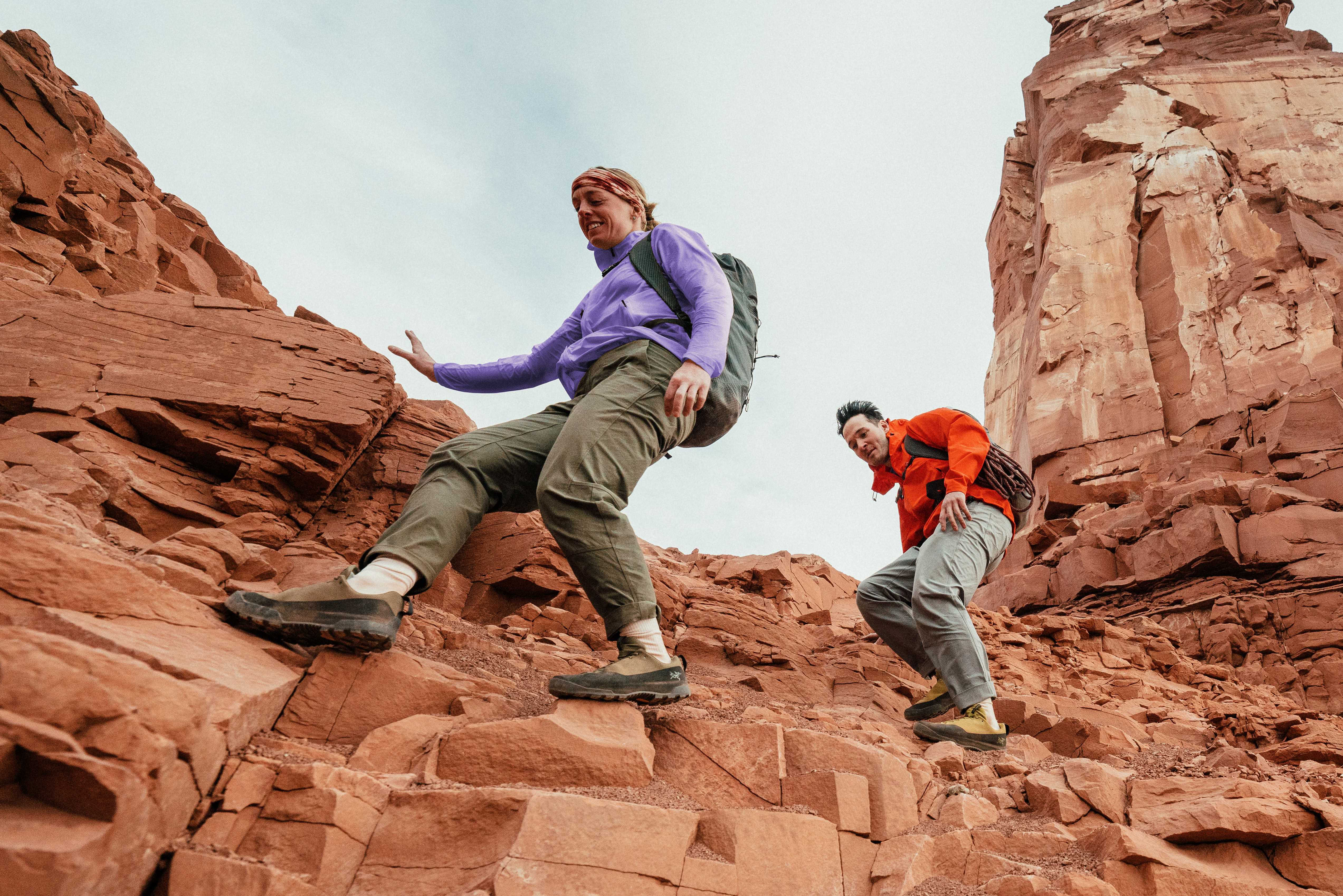 two people are hiking up a rocky mountain .