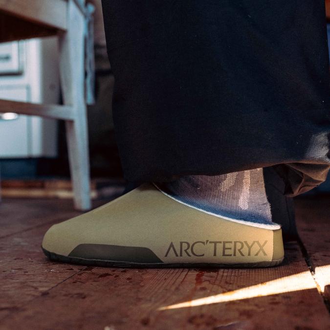 Olive Arc'teryx slip-on shoe on a wooden floor.