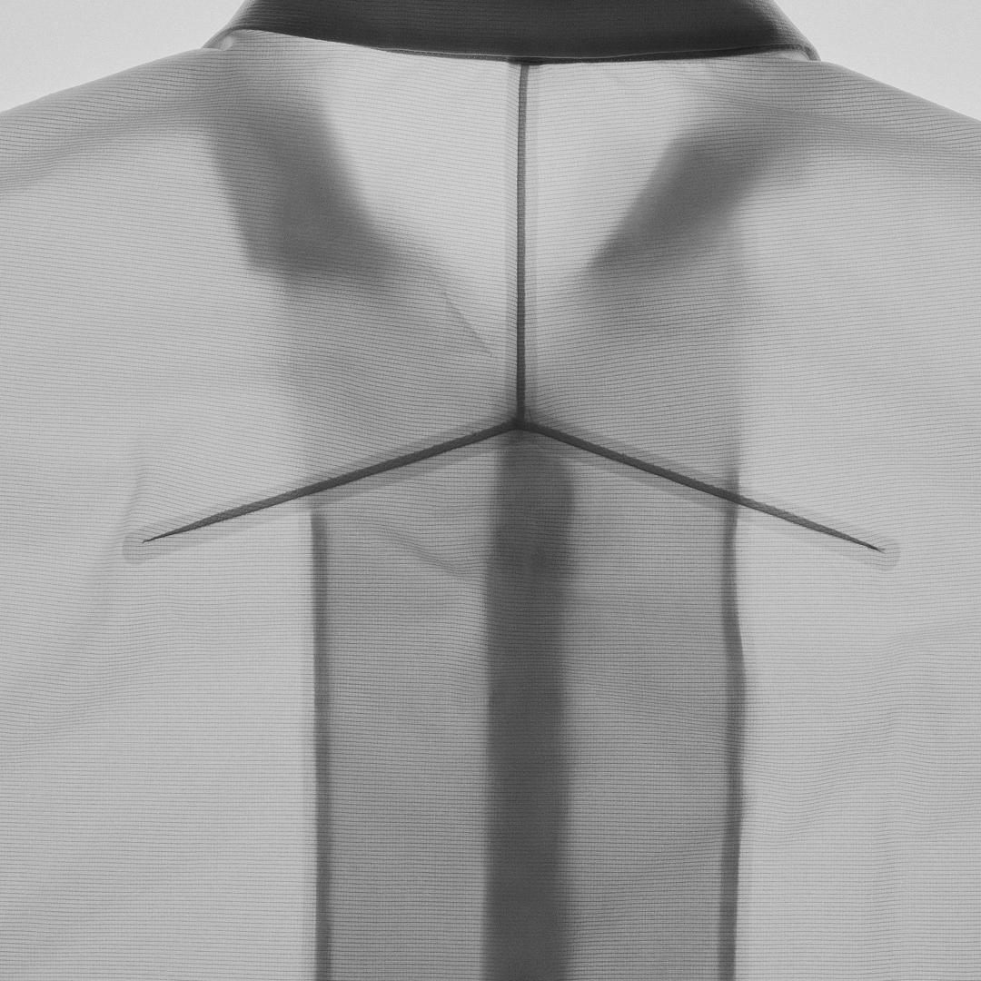 Back of a translucent white shirt revealing the dark outline of a hanger.