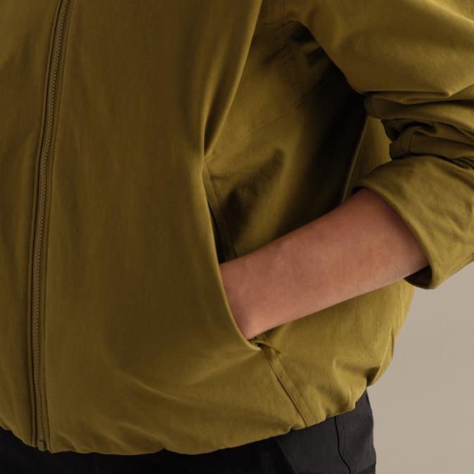 A person's arm in the pocket of a green zipped jacket.