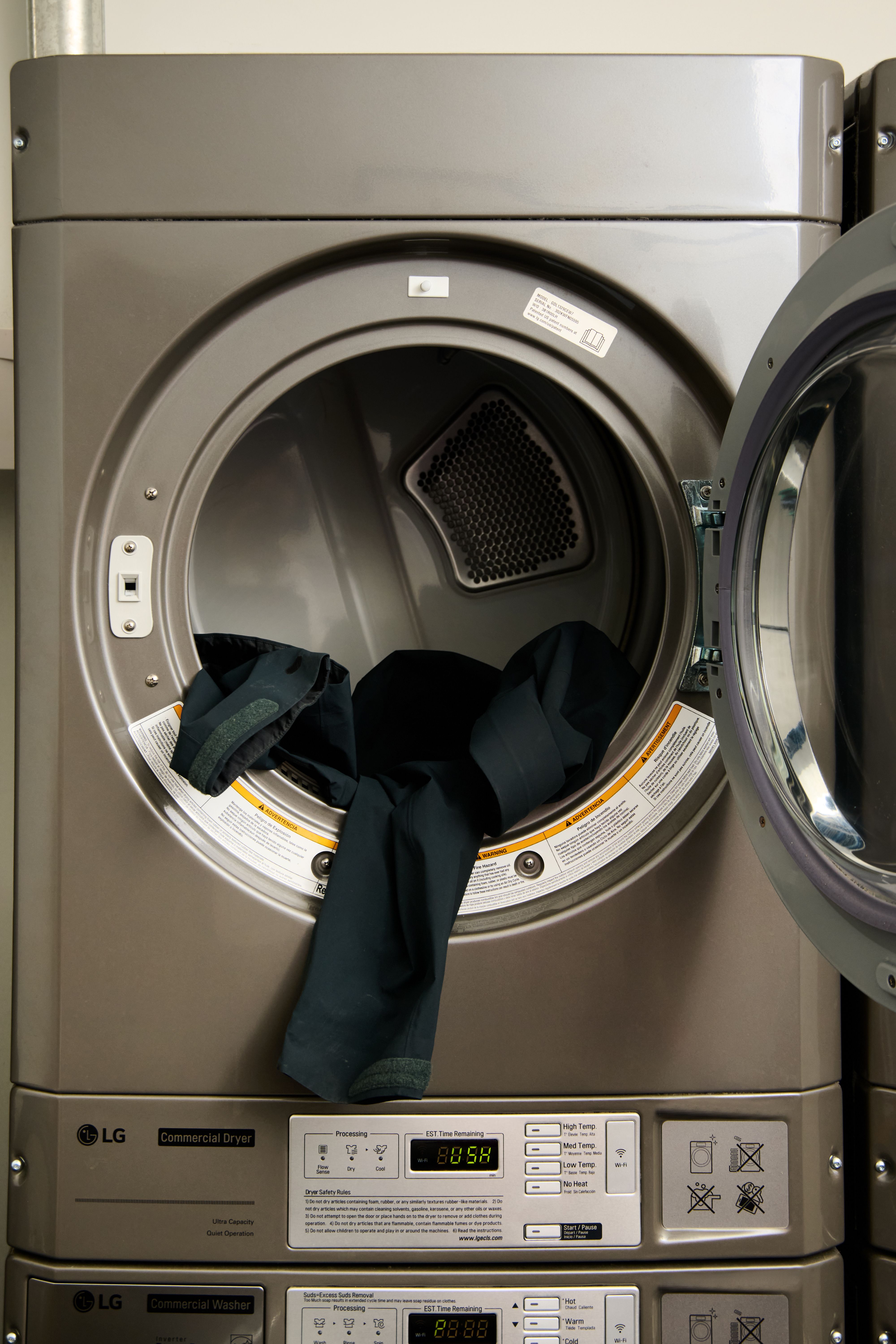 Open commercial dryer with dark clothing inside.