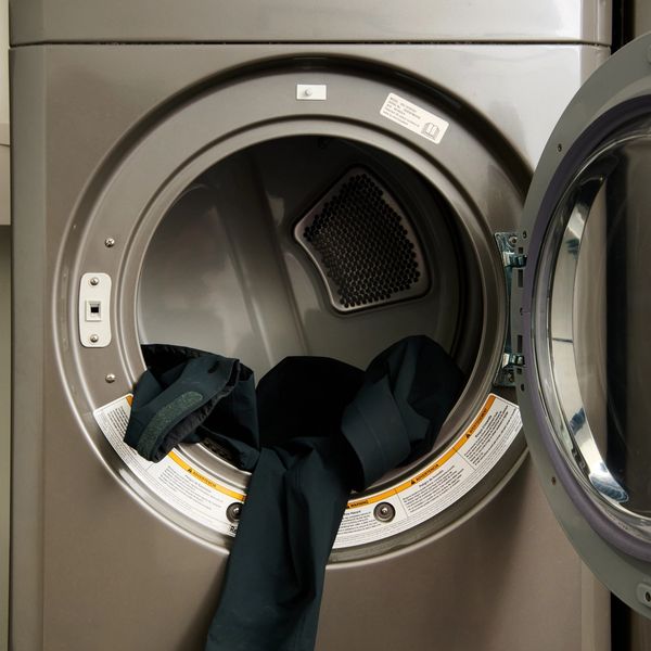 Open commercial dryer with dark clothing inside.