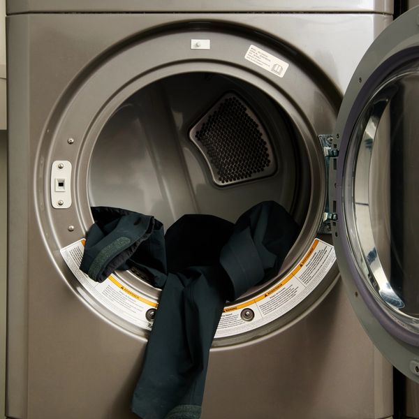A dark garment sits inside an open LG commercial dryer, stacked above a matching washer.