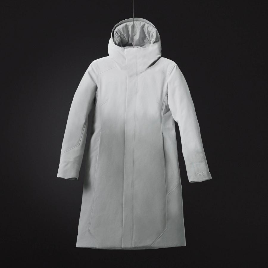 a white coat with a hood is hanging on a black background .