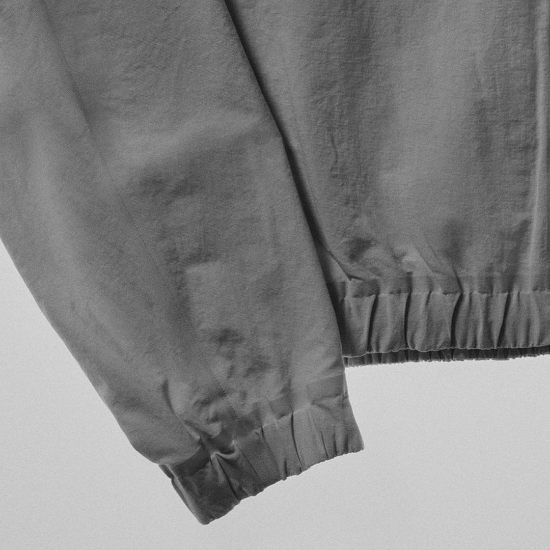 Gray garment with an elastic sleeve cuff and ruched elastic hem.