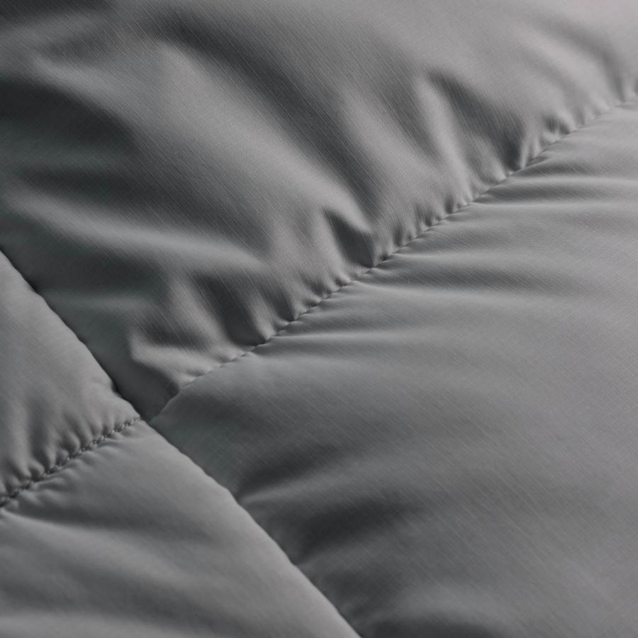 a close up of a grey comforter on a bed .