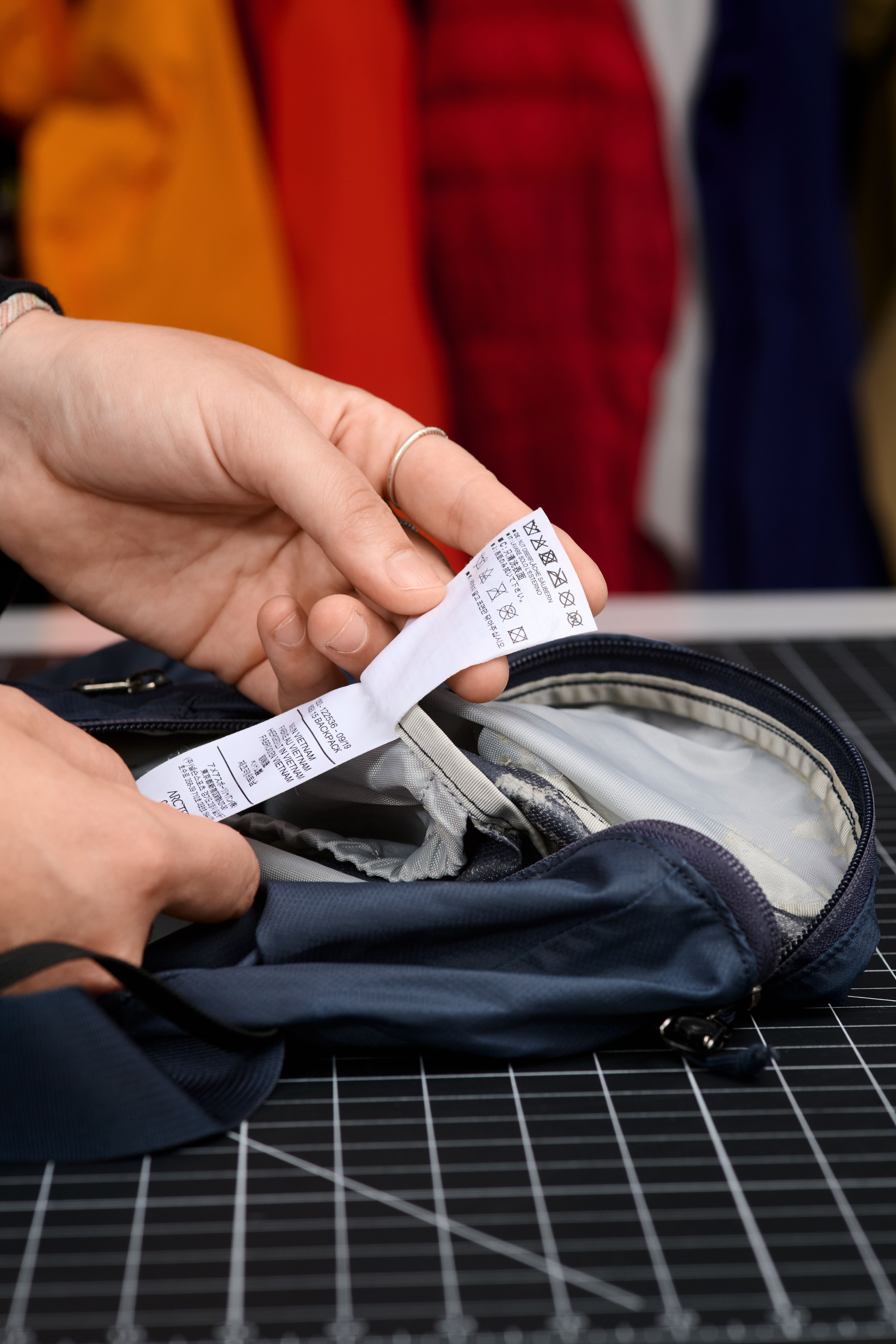 Person's hands examining a white clothing label inside a dark blue bag.