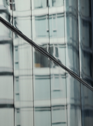 Reflective glass building facade with a diagonal line and wavy reflections.