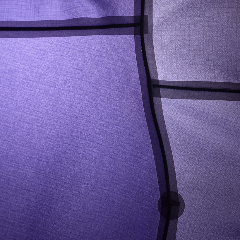Purple sheer fabric with dark grid lines, a curved seam, and a dark circular detail.